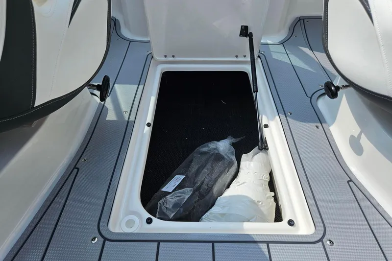 Slide: The Image of 2025 Chaparral 23 SSi boat storage compartment with open hatch and stored items. - 11