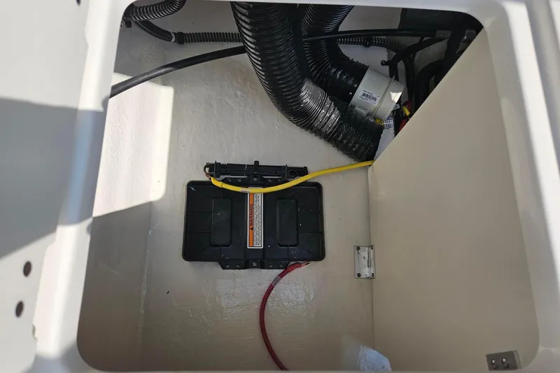 Slide: The Image of 2025 Chaparral 23 SSi boat battery compartment with wiring and ventilation hoses. - 18
