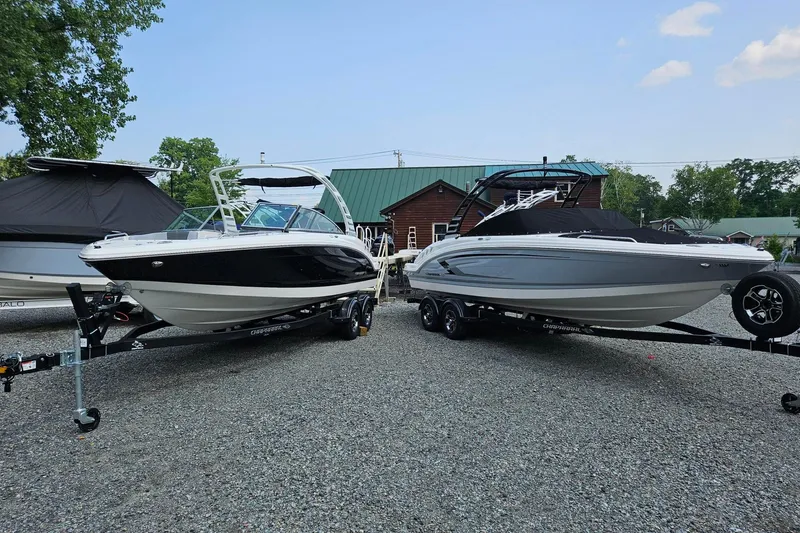 Slide: The Image of 2025 Chaparral 23 SSi boats on trailers, parked outdoors on gravel. - 2