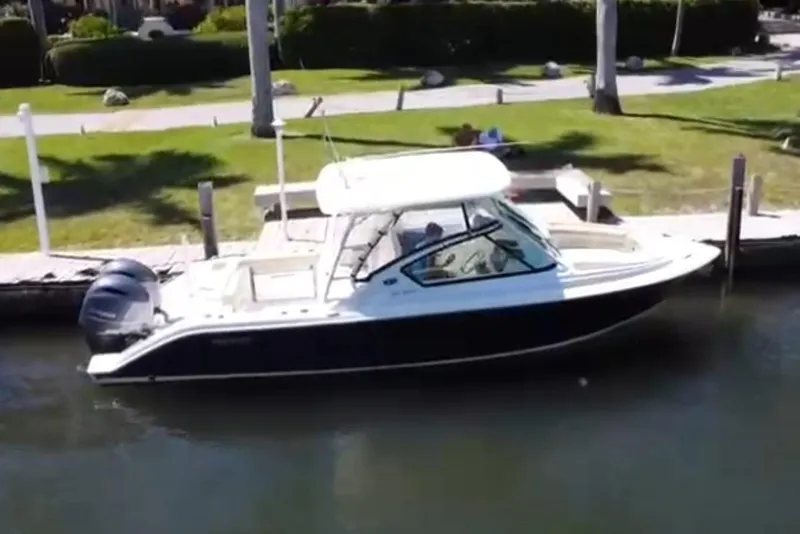 Slide: The Image of 2020 Pursuit DC 266 Dual Console interior with covered helm, docked by the water. - 16