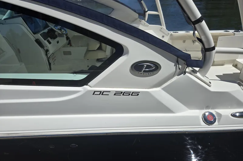 Slide: The Image of 2020 Pursuit DC 266 Dual Console boat docked by lush greenery. - 2