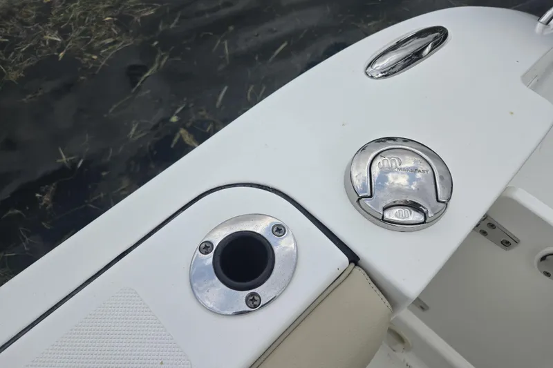 Slide: The Image of 2020 Pursuit DC 266 Dual Console boat interior with seating, docked by a scenic waterfront. - 27