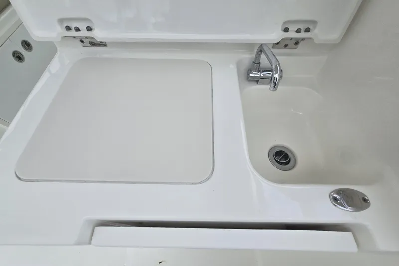 Slide: The Image of 2020 Pursuit DC 266 Dual Console boat interior with open storage compartment and sink. - 31