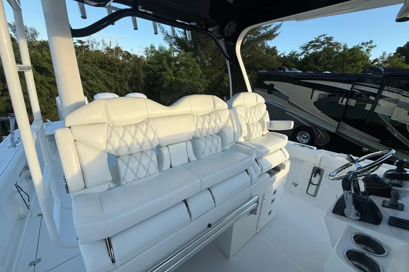 Slide: The Image of 2018 Edgewater 370CC boat interior with fishing rod holders and storage, parked at marina. - 10
