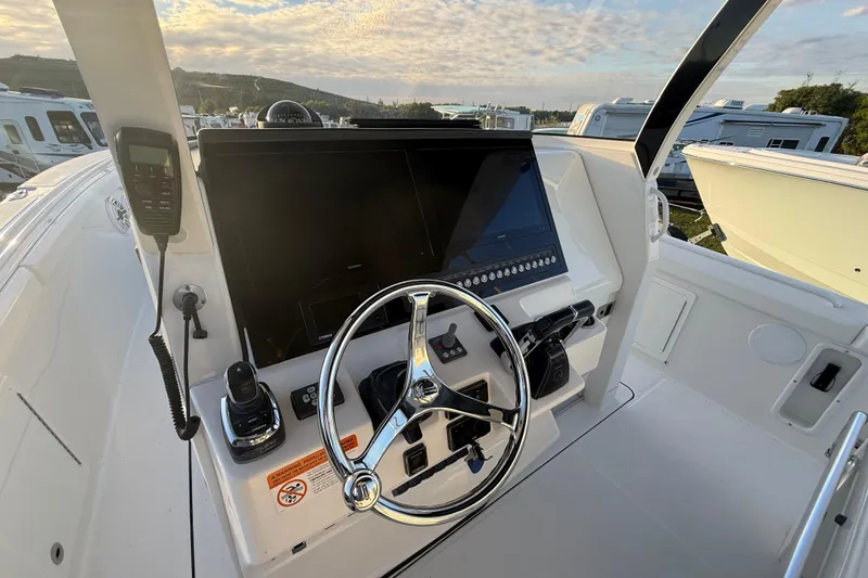 Slide: The Image of 2018 Edgewater 370CC boat helm with steering wheel, control panel, and cup holders at sunset. - 11