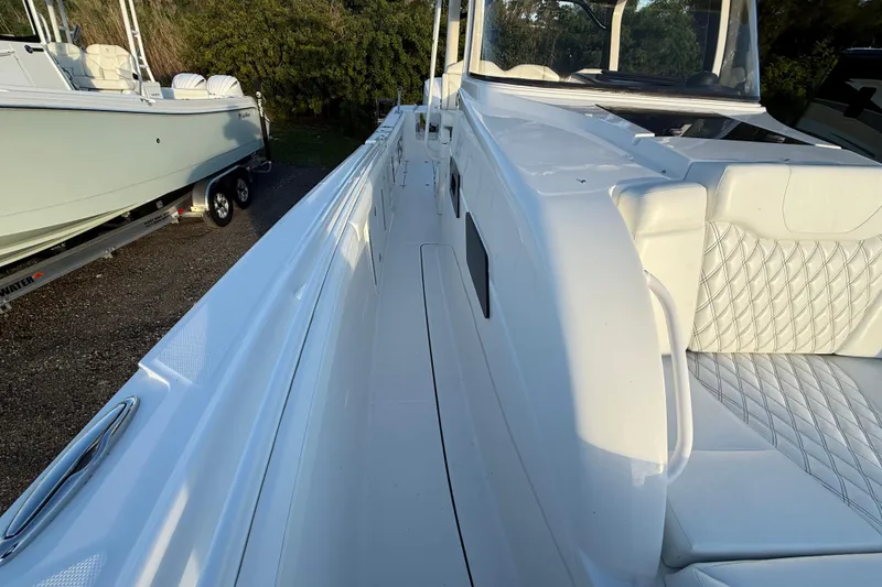 Slide: The Image of 2018 Edgewater 370CC boat interior with white seating and table, parked near RVs under a cloudy sky. - 14