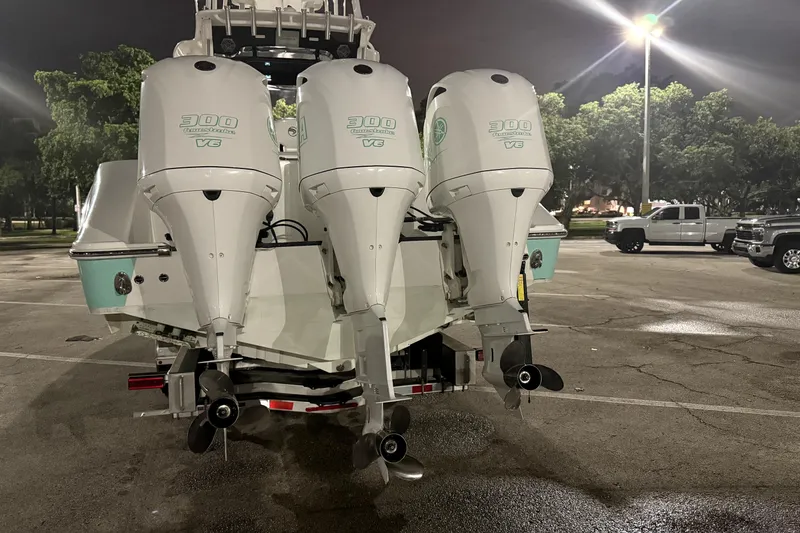 Slide: The Image of 2018 Edgewater 370CC boat docked by palm trees and waterfront homes. - 2