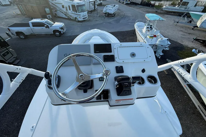 Slide: The Image of 2018 Edgewater 370CC boat helm with steering wheel and controls, parked near RVs and trucks. - 25