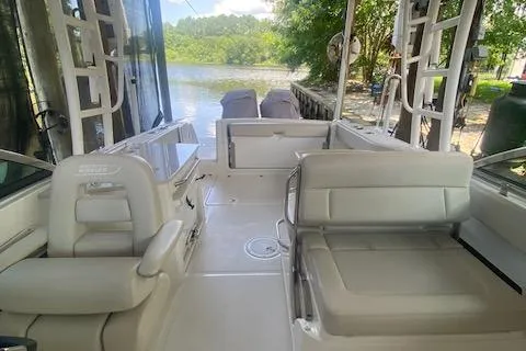 Slide: The Image of 2017 Boston Whaler 270 Vantage boat interior with seating, docked by a scenic river. - 13