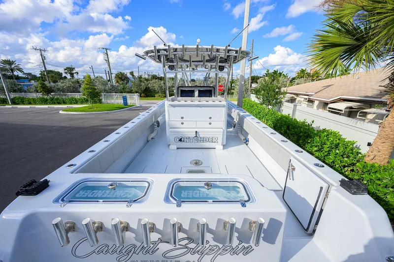 Slide: The Image of 2022 Contender 39 ST boat with spacious deck, rod holders, and clear sky background. - 23