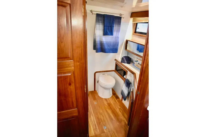 Slide: The Image of 1987 Californian 55 Cockpit Motor Yacht bathroom with wooden accents and blue decor. - 17