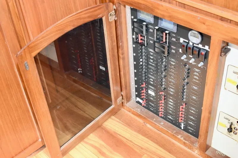 Slide: The Image of Electrical panel inside 1987 Californian 55 Cockpit Motor Yacht, featuring wooden cabinetry. - 29