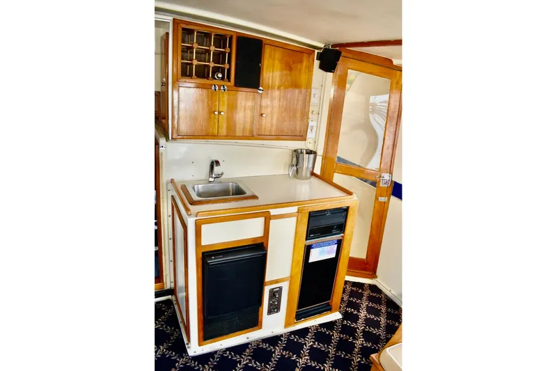 Slide: The Image of 1987 Californian 55 Cockpit Motor Yacht interior kitchen with wooden cabinets and compact appliances. - 3