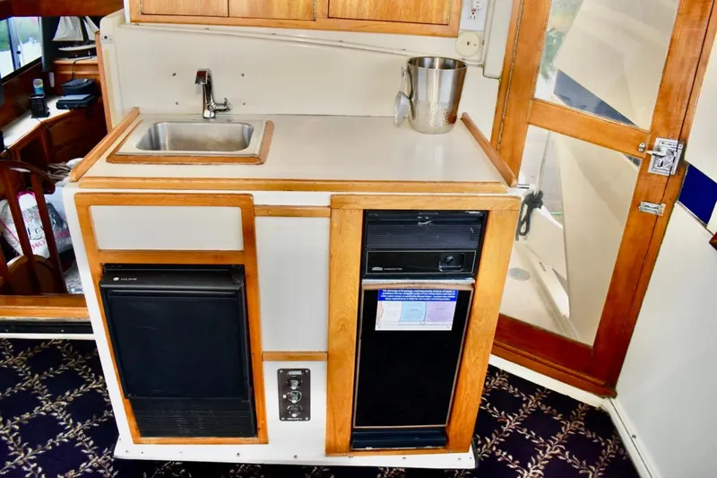 Slide: The Image of 1987 Californian 55 Cockpit Motor Yacht interior with sink, mini-fridge, and wooden cabinetry. - 5
