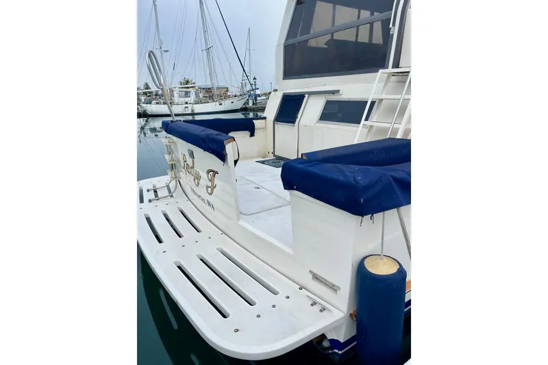 Slide: The Image of 1987 Californian 55 Cockpit Motor Yacht docked, featuring spacious deck and blue accents. - 9