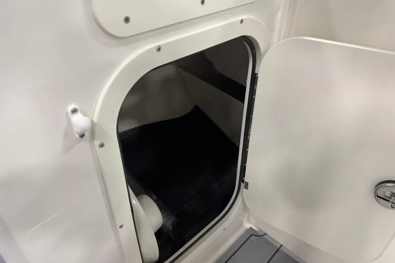Slide: The Image of 2026 Chaparral 23 SSi boat storage compartment with open door, showcasing interior space. - 56