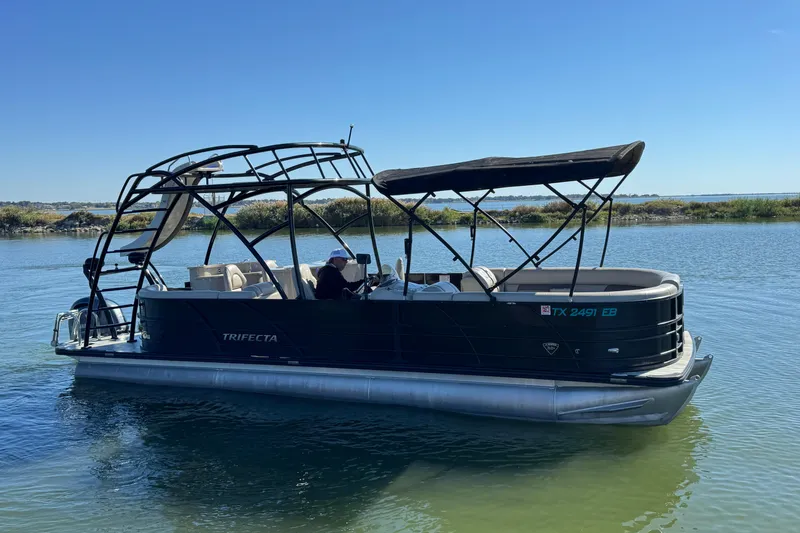 Slide: The Image of 2018 Trifecta SS 27RFE UDS XR pontoon boat on calm water under clear blue sky. - 3