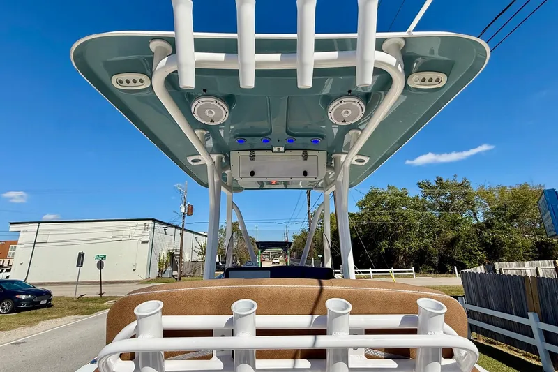 Slide: The Image of 2023 Sea Hunt Ultra 234 boat with T-top and rod holders, parked outdoors. - 11