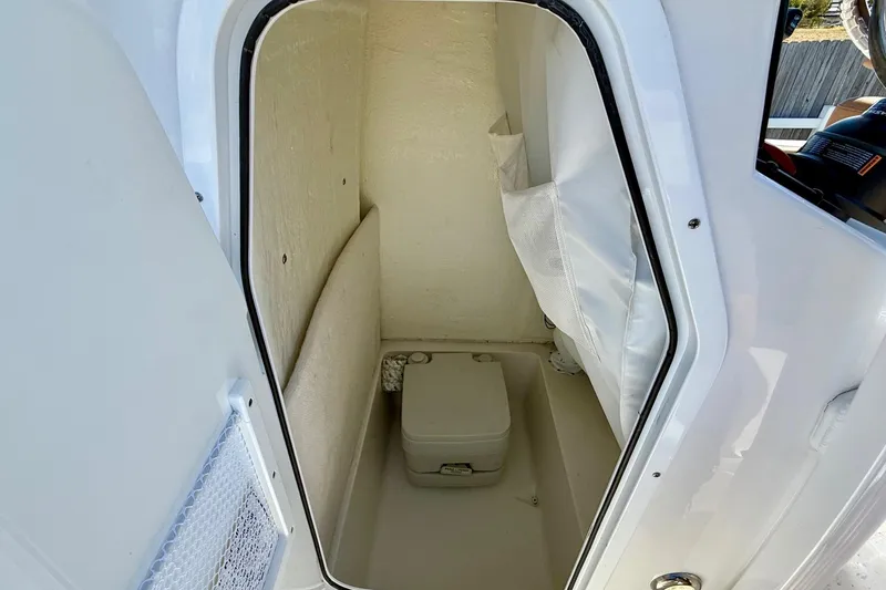 Slide: The Image of 2023 Sea Hunt Ultra 234 boat interior with compact toilet compartment. - 13