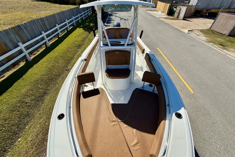 Slide: The Image of 2023 Sea Hunt Ultra 234 boat with brown seating, parked on a road near a wooden fence. - 16