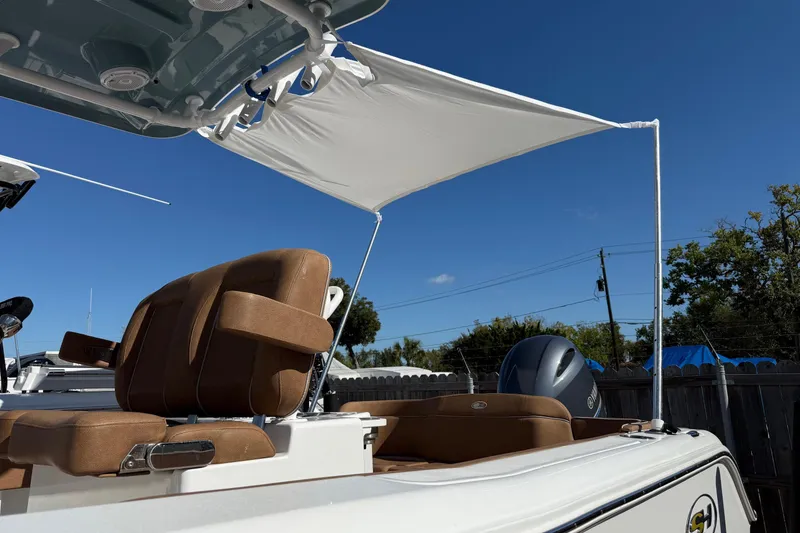 Slide: The Image of 2023 Sea Hunt Ultra 234 boat with canopy and brown seating under clear blue sky. - 22
