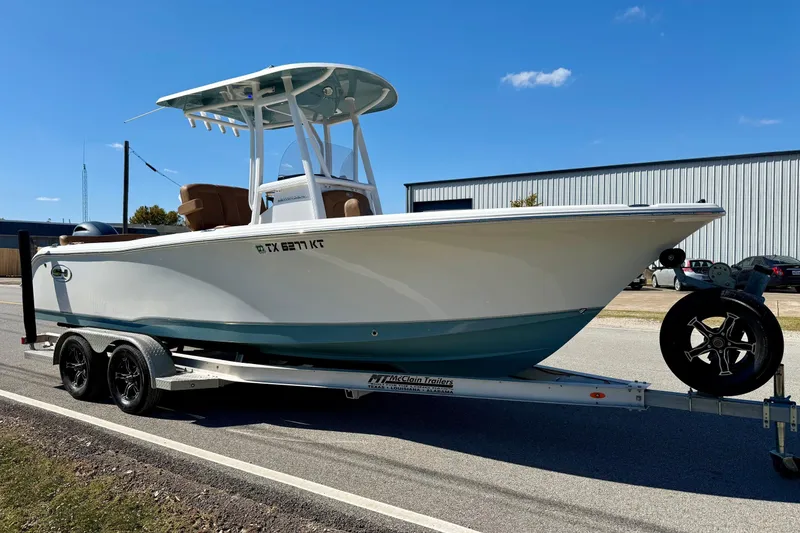 Slide: The Image of 2023 Sea Hunt Ultra 234 boat on trailer, parked outdoors under clear blue sky. - 5