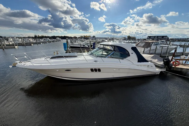 Slide: The Image of 2007 Sea Ray 44 Sundancer yacht docked at a marina under a partly cloudy sky. - 2