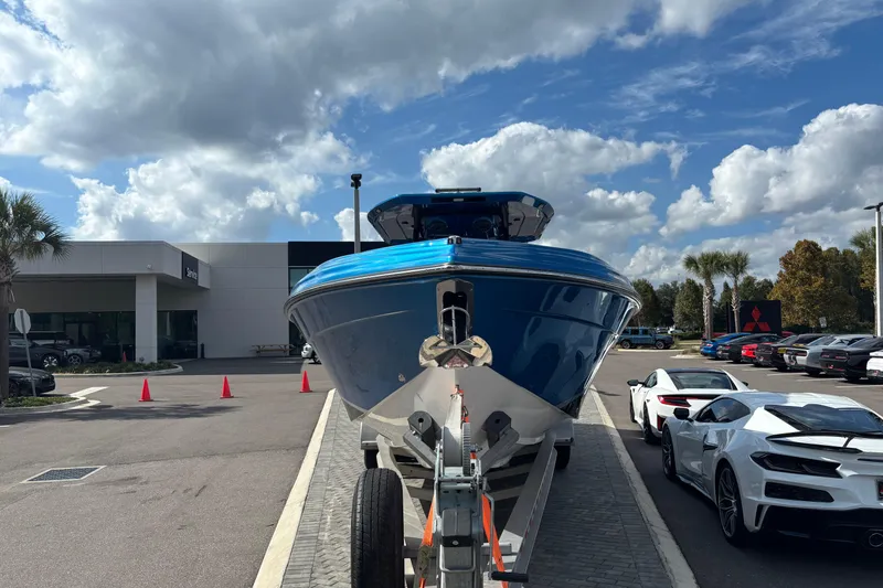Slide: The Image of 2024 GSX 36 boat in vibrant blue on a trailer, parked outdoors under a cloudy sky. - 2