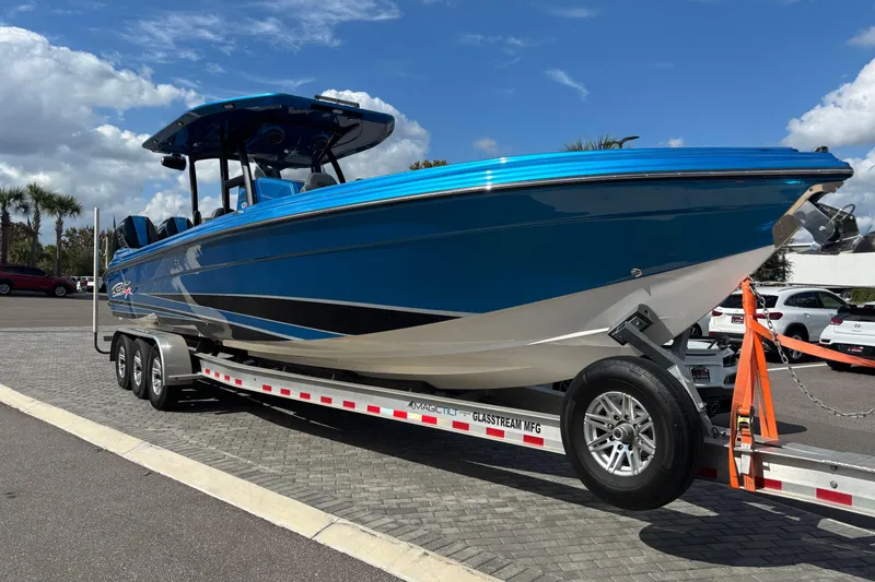The Image of 2024 GSX 36 boat in vibrant blue on a trailer, parked outdoors under a cloudy sky. - 0