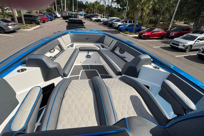 Slide: The Image of 2024 GSX 36 boat interior with gray seating, blue accents, and parked cars in the background. - 24