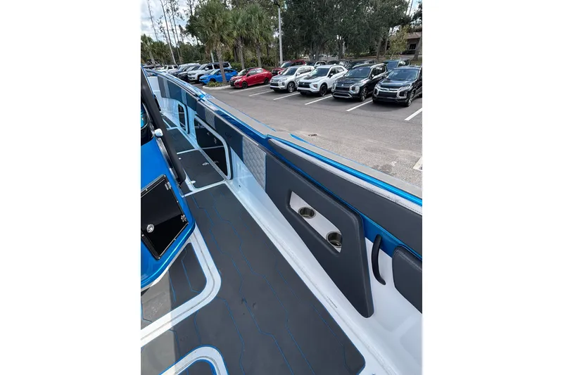 Slide: The Image of 2024 GSX 36 boat interior with sleek blue and gray design, parked near cars. - 32