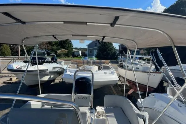 Slide: The Image of 2023 Zodiac N-ZO 680 boat with canopy, docked among other boats under a clear sky. - 16