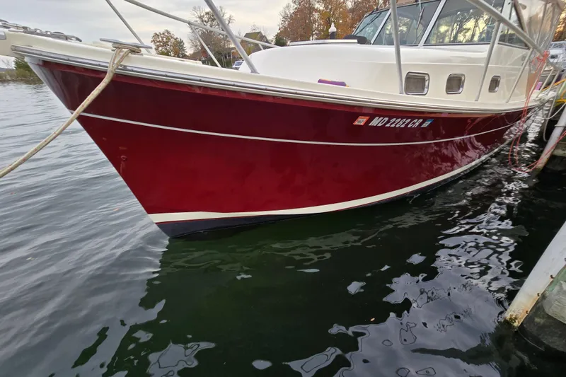 Slide: The Image of 2001 Mainship 30 Pilot Rum Runner boat with striped seating and canopy on calm water. - 12