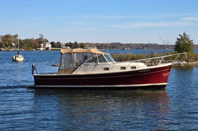 Slide: The Image of 2001 Mainship 30 Pilot Rum Runner cockpit with striped seating, steering wheel, and water view. - 2