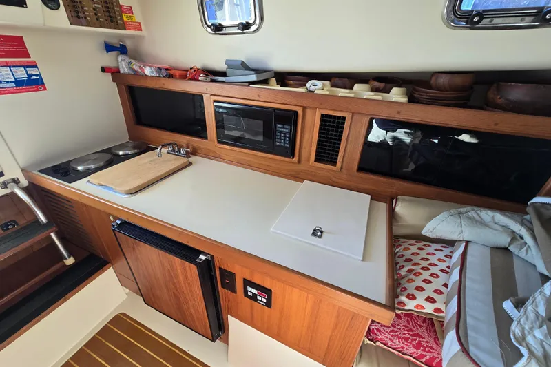 Slide: The Image of 2001 Mainship 30 Pilot Rum Runner galley with stove, microwave, and compact design. - 36