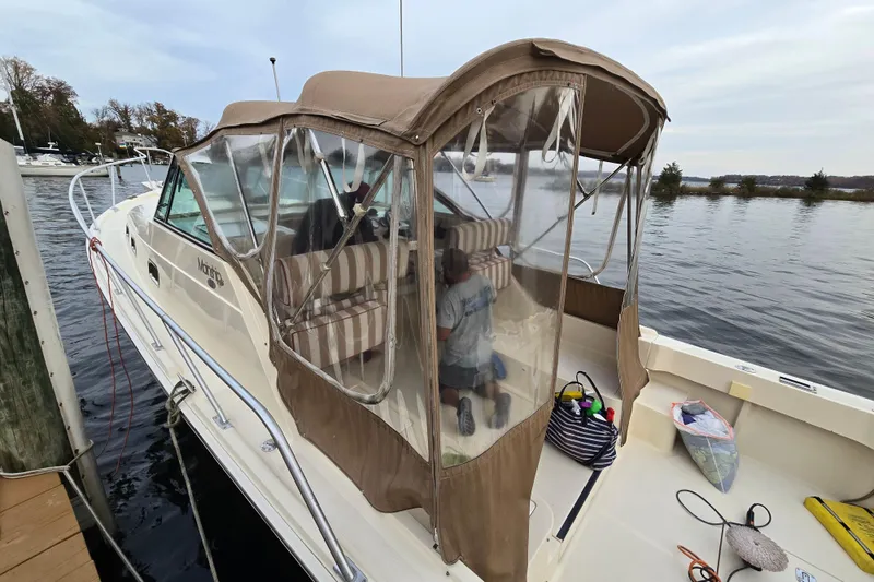 Slide: The Image of 2001 Mainship 30 Pilot Rum Runner boat interior with covered seats and calm water backdrop. - 9