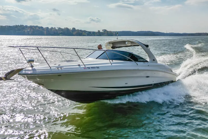 The Image of 2007 Sea Ray 290 Sun Sport cruising on a sunny lake with scenic background. - 0