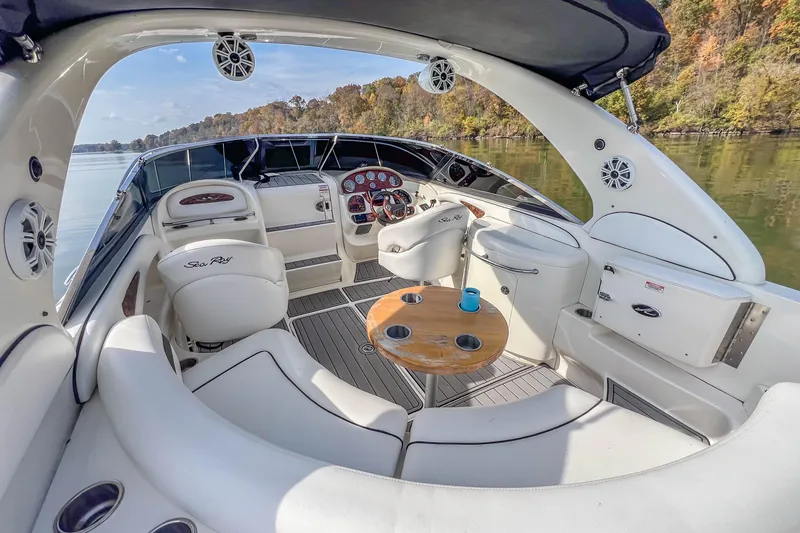 Slide: The Image of 2007 Sea Ray 290 Sun Sport boat interior with seating, table, and dashboard on a calm lake. - 17