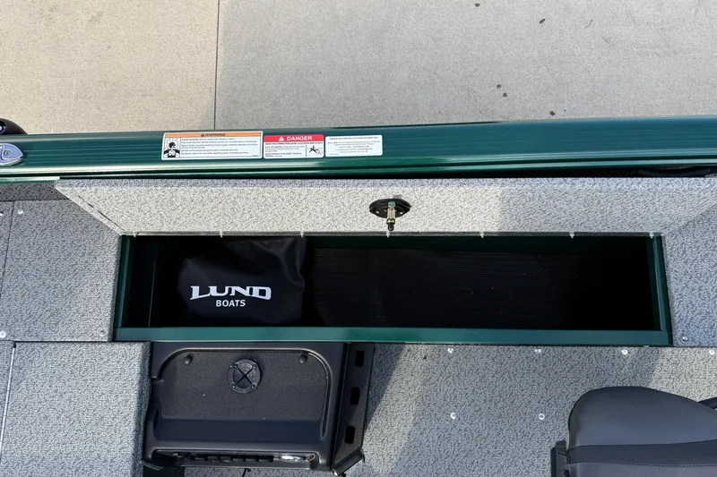 Slide: The Image of 2026 Lund 1700 Explorer Tiller boat storage compartment with Lund Boats branding. - 15
