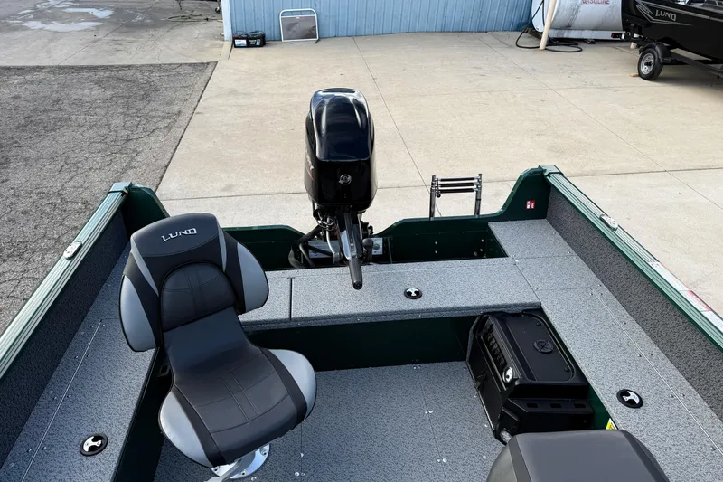 Slide: The Image of 2026 Lund 1700 Explorer Tiller boat interior with seating and motor, docked outdoors. - 16