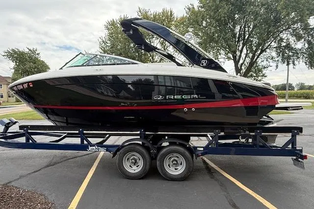 Slide: The Image of 2021 Regal LS4 Surf boat on trailer, black and red design, parked outdoors. - 3
