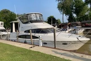 The Image of 2001 Carver 396 Motor Yacht docked at a marina, surrounded by trees and other boats. - 0