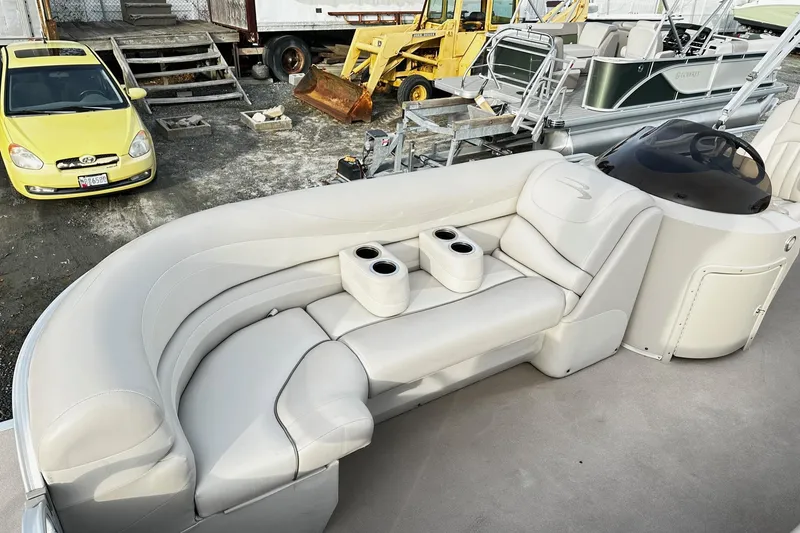 Slide: The Image of 2015 Bennington 2275GS Pontoon with beige seating and cup holders, parked near vehicles. - 13