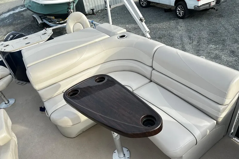 Slide: The Image of 2015 Bennington 2275GS Pontoon boat interior with beige seating and dark wood table. - 15