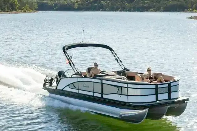 Slide: The Image of 2025 Barletta L23UC pontoon boat cruising on a scenic lake. - 9