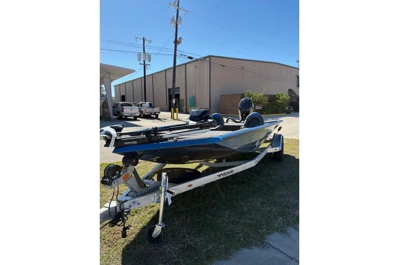 Slide: The Image of 2026 Vexus AVX181 boat on trailer, parked outdoors near industrial building. - 2