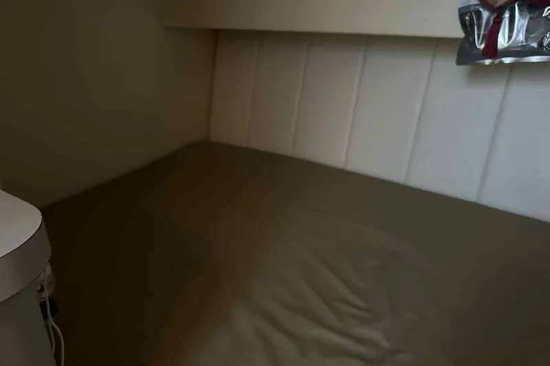 Slide: The Image of 1993 Mainship 39 Express cabin interior with bed and storage area. - 18