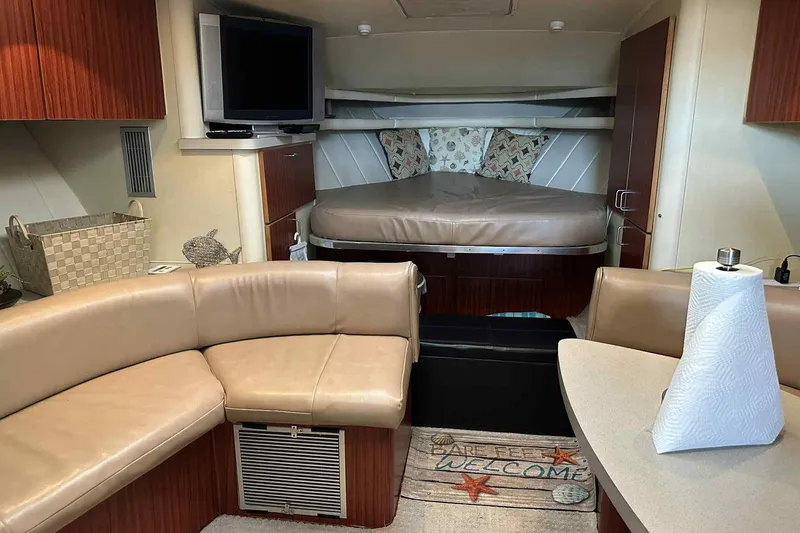Slide: The Image of 1993 Mainship 39 Express interior with cozy seating, bed, TV, and welcome mat. - 20