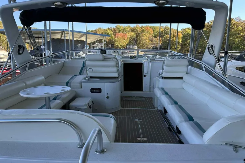 Slide: The Image of 1993 Mainship 39 Express yacht interior with white seating and table, docked outdoors. - 42