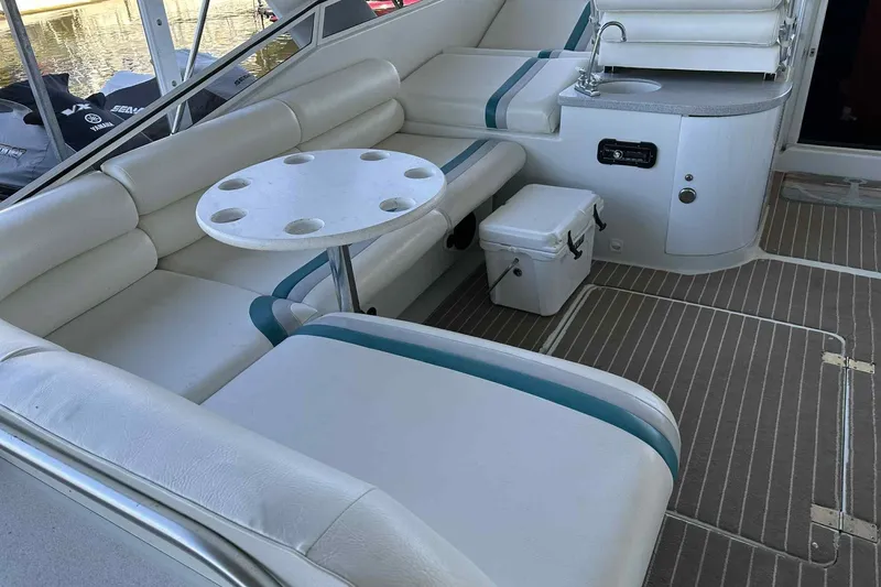 Slide: The Image of 1993 Mainship 39 Express interior with white seating, table, and compact sink area. - 5